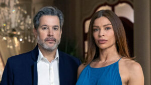 Ferette (Murilo Benício) de terno azul e Arminda (Grazi Massafera) de vestido azul posam sérios em foto da novela Três Graças