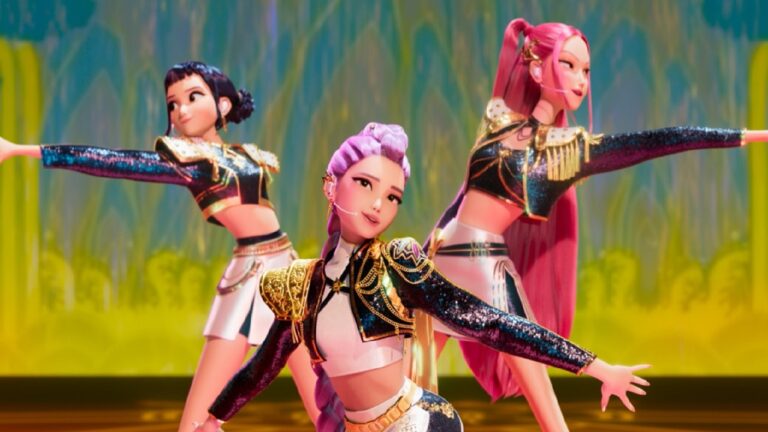 Cena do filme Guerreiras do K-Pop mostra três personagens animadas dançando em coreografia, com figurinos brilhantes e coloridos em um palco iluminado