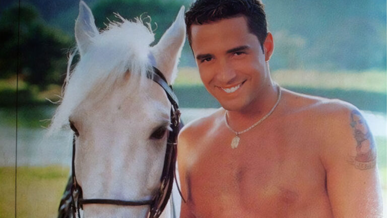 O cantor Latino sem camisa sorri ao lado de um cavalo branco com rédeas escuras em ensaio fotográfico para a revista G Magazine