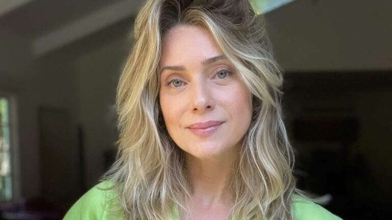 Letícia Spiller de cabelos ondulados e olhar sereno posa em ambiente interno iluminado pela luz natural usando blusa verde clara