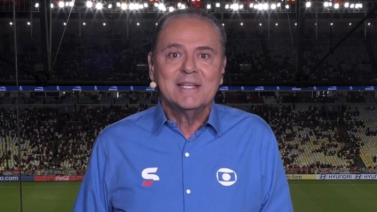 Luis Roberto com camisa azul da Globo em cabine de transmissão no Estádio do Maracanã