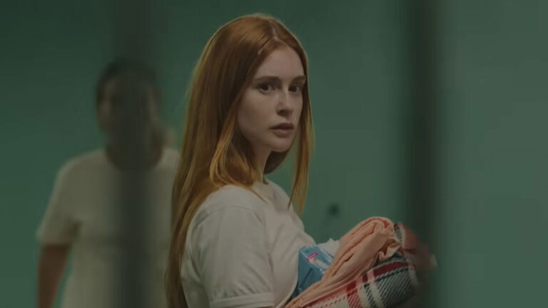Atriz Marina Ruy Barbosa caracterizada como Suzane von Richthofen em cena da série Tremembé; ela segura roupas e olha por cima do ombro