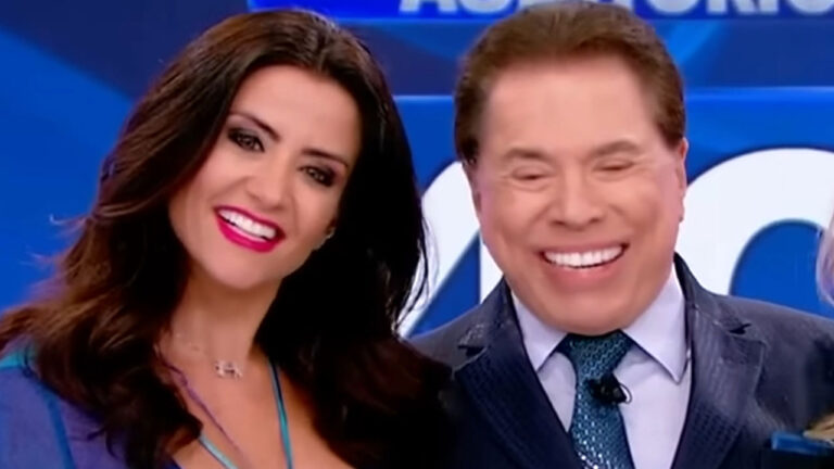 A assistente de palco Patricia Salvador e Silvio Santos sorriem lado a lado no estúdio do Programa Silvio Santos, atração do SBT