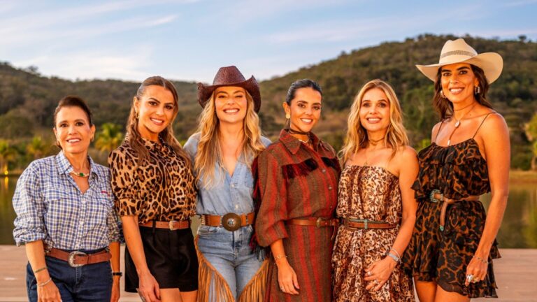 Seis mulheres posam sorrindo ao ar livre em frente a paisagem de cerrado usando roupas com estilo country em cena de divulgação do programa Poderosas do Cerrado