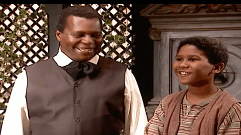 Cena da novela Terra Nostra mostra dois personagens sorrindo lado a lado em um ambiente com decoração clássica e plantas ao fundo