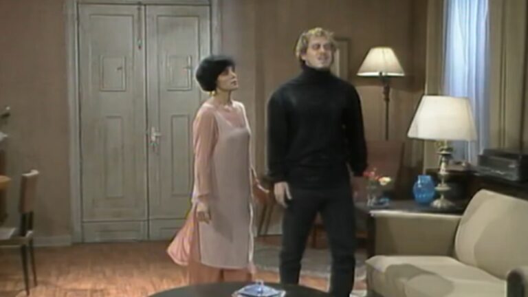 Homem e mulher conversam em uma sala de estar, em cena dramática da novela A Viagem