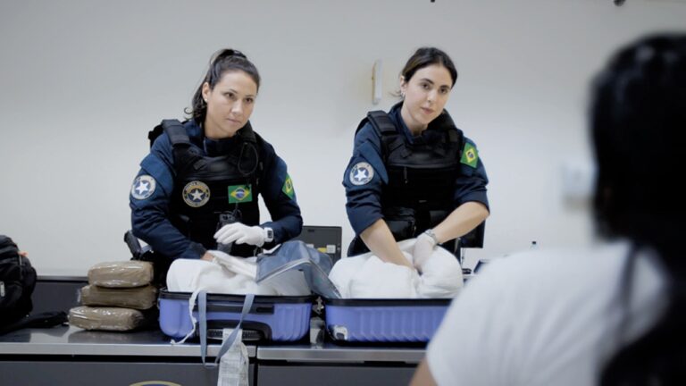 Duas agentes da polícia apreendem drogas em malas abertas durante fiscalização em aeroporto