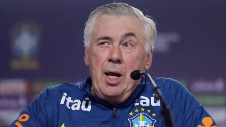 Homem com agasalho da Seleção Brasileira fala ao microfone durante coletiva de imprensa