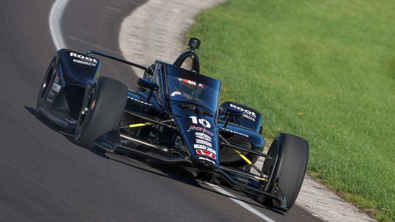 Carro de Fórmula Indy na cor preta, de número 10, pilotado por Álex Palou em alta velocidade na pista de corrida
