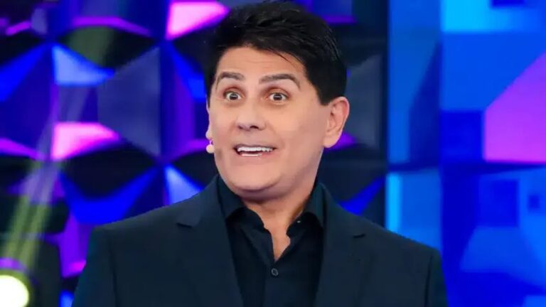 Homem de terno escuro e microfone de lapela aparece com expressão surpresa