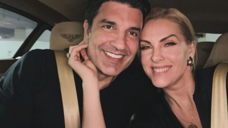 Edu Guedes e Ana Hickmann sorrindo dentro de um carro. Eles estão sentados nos bancos dianteiros, usando cinto de segurança, e aparecem bem próximos um do outro, em clima de intimidade e alegria