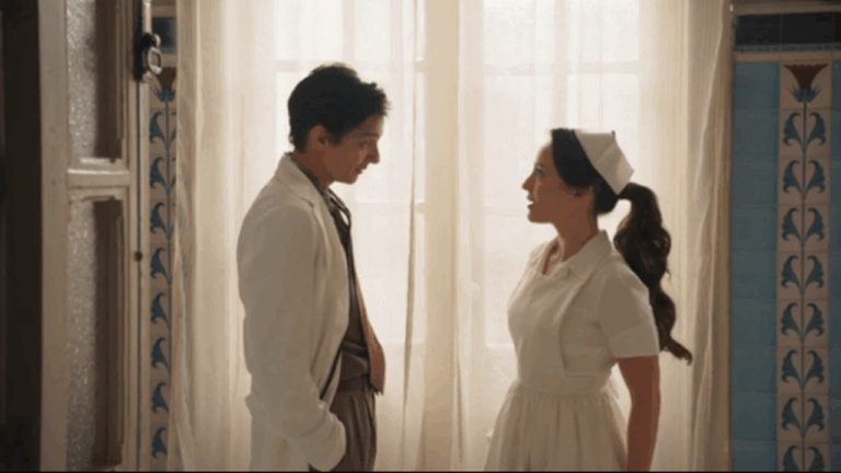 Homem de jaleco e enfermeira conversam em cena iluminada pela janela na novela Êta Mundo Melhor!