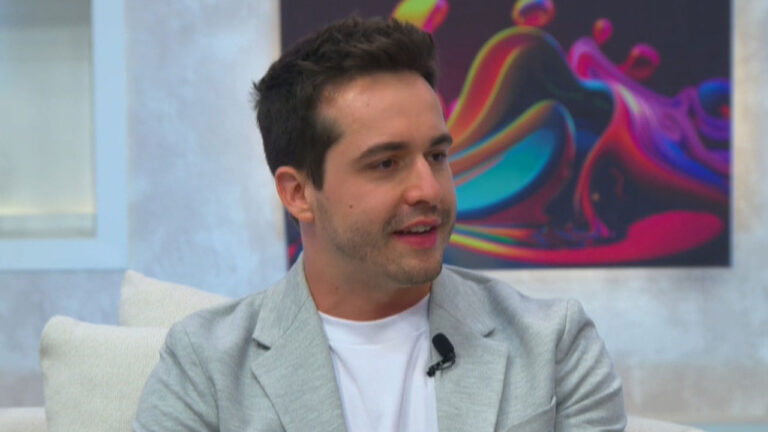 Igor Faria, filho de Rinaldi Faria, usando camiseta branca e blazer claro em entrevista em um sofá