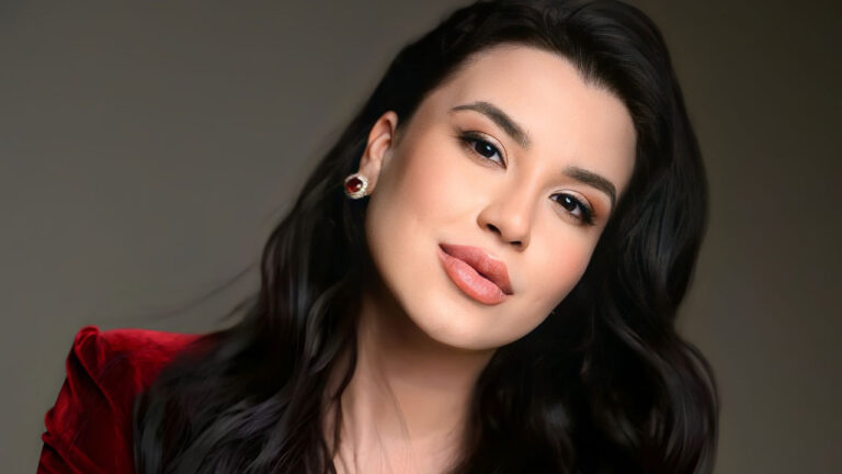 Sensitiva Izadora Morais com cabelo castanho escuro ondulado, usando blazer vermelho e maquiagem destacada