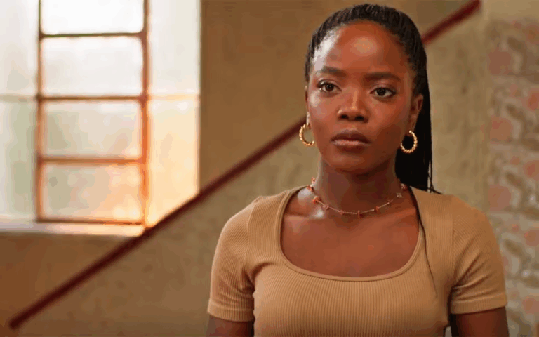 Leo com uma roupa marrom e uma escadaria atrás