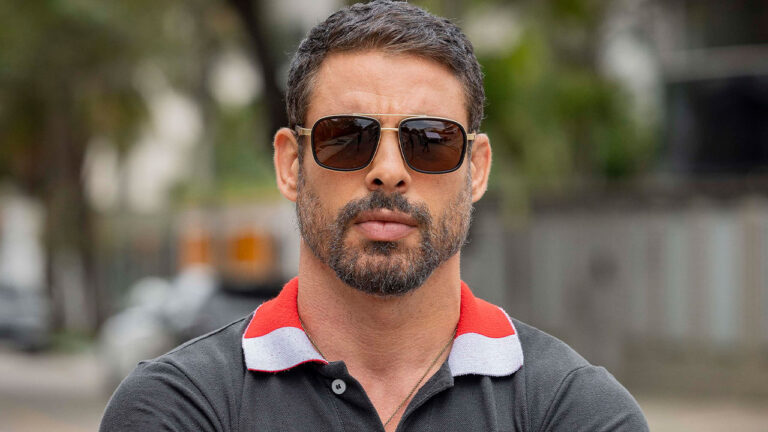 Cauã Reymond como o protagonista Maurício, com barba, óculos escuros e camisa polo na série Jogada de Risco