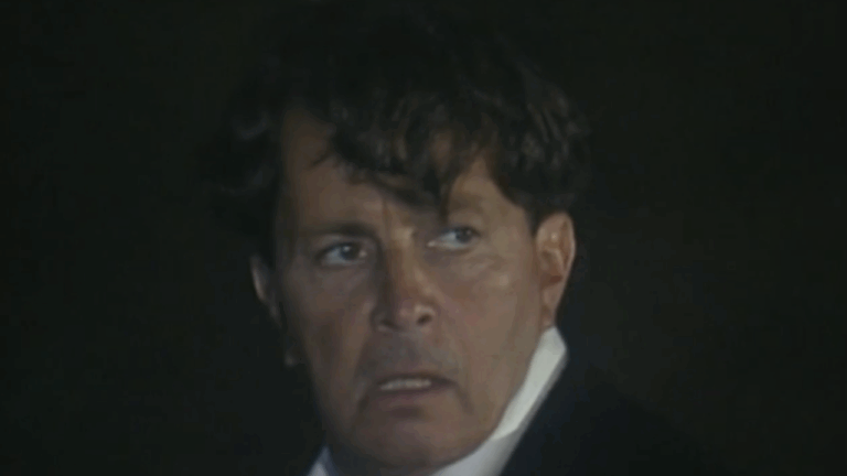 Cena da novela Rainha da Sucata mostra um homem com expressão tensa e olhar assustado, em ambiente escuro e de clima misterioso