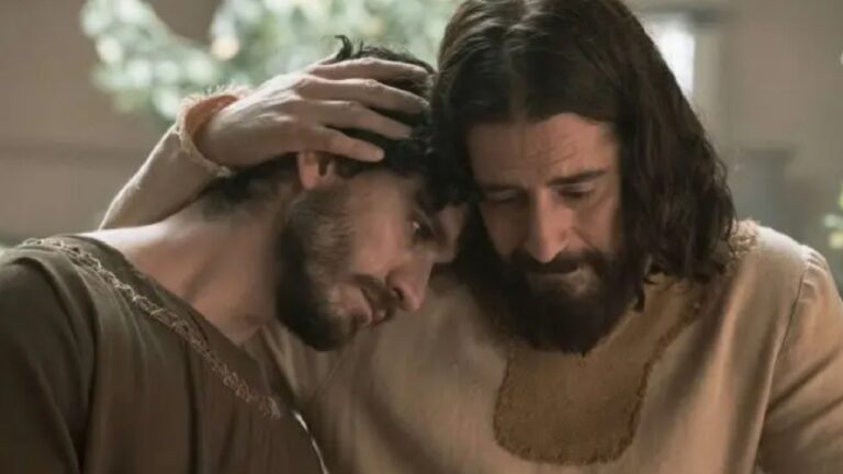 Cena de época mostra dois homens com expressão de tristeza e consolo; um deles abraça o outro, que apoia a cabeça em seu ombro, em ambiente iluminado naturalmente