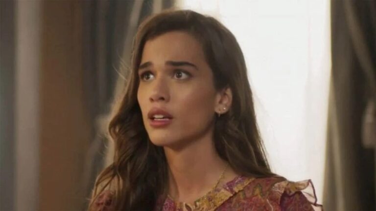 Jovem com expressão de preocupação em ambiente interno iluminado, usando blusa estampada de tons quentes