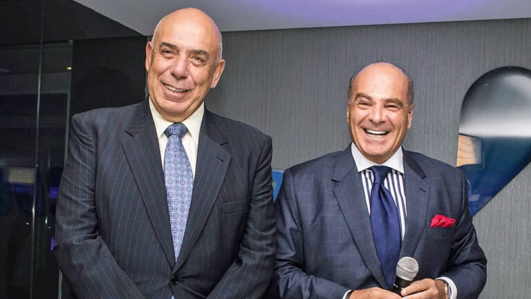 Amilcare Dallevo Jr. e Marcelo de Carvalho sorriem de terno lado a lado em evento corporativo da RedeTV! com Marcelo segurando microfone