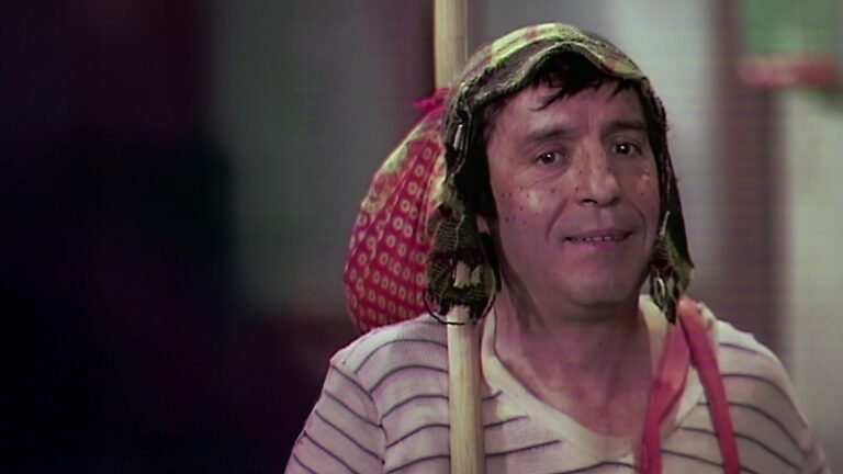 Imagem do personagem Chaves com gorro e camiseta listrada segurando um bastão com trouxa em cena da série mexicana