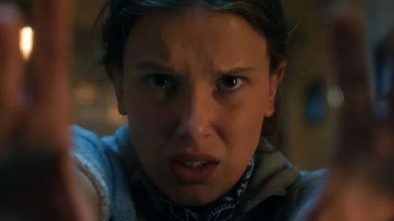 Adolescente olha fixamente para a frente com expressão tensa e concentrada, mantendo as mãos erguidas como se estivesse empurrando algo ou usando força intensa. A cena tem iluminação baixa e clima dramático, sugerindo momento de grande esforço ou tensão emocional