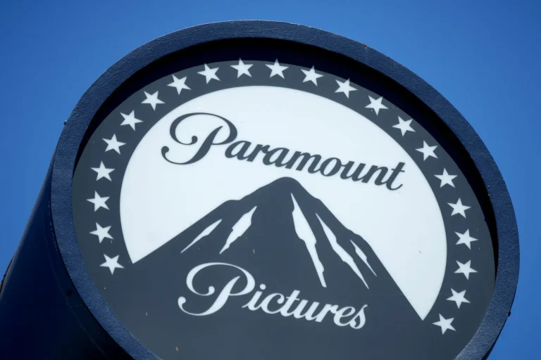 Logotipo da Paramount Pictures em um letreiro circular, exibindo uma montanha central estilizada cercada por estrelas, sobre fundo azul claro.