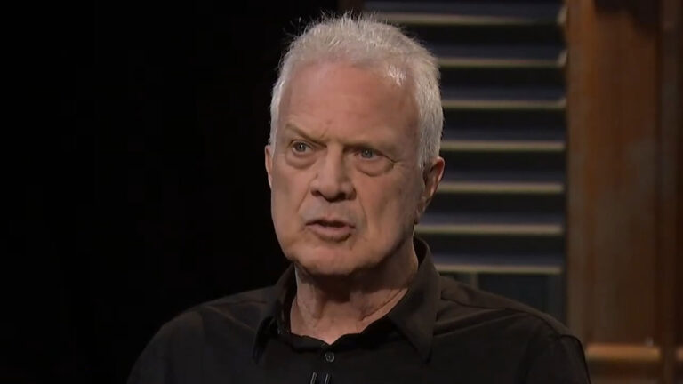 Pedro Bial de cabelos brancos e camisa preta olha sério para a frente em cenário do programa Provoca com fundo escuro