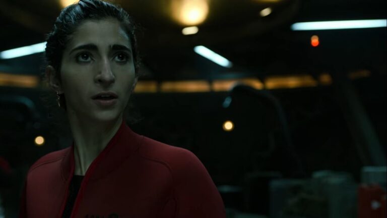 Mulher com expressão preocupada veste macacão vermelho em ambiente escuro e tecnológico, iluminado por luzes artificiais suaves