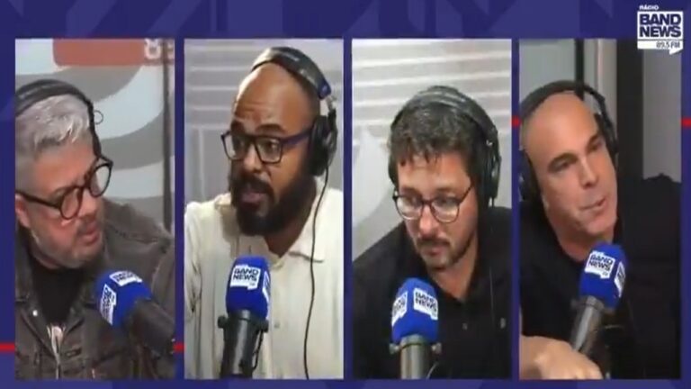 Quatro homens participam de um programa de rádio, cada um falando ao microfone identificado com o logotipo da Rádio BandNews FM; todos usam fones de ouvido e parecem debater um tema em estúdio.