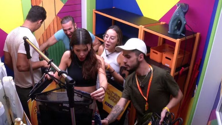 Participantes do Big Brother Brasil reunidos em bastidor colorido manuseiam equipamentos e fios durante preparação de dinâmica