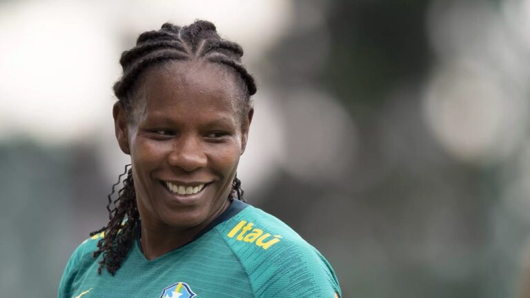 Jogadora da Seleção Brasileira feminina sorri durante treino vestindo uniforme verde com logotipo da CBF