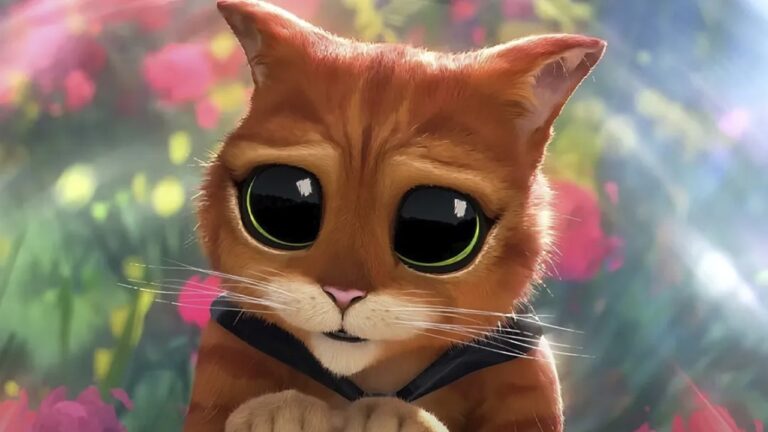 Imagem do personagem animado Gato de Botas, com expressão de súplica e olhos grandes e brilhantes. Ele aparece em close, com fundo colorido de flores desfocado, em uma cena típica de apelo cômico e emocional dos filmes da franquia.
