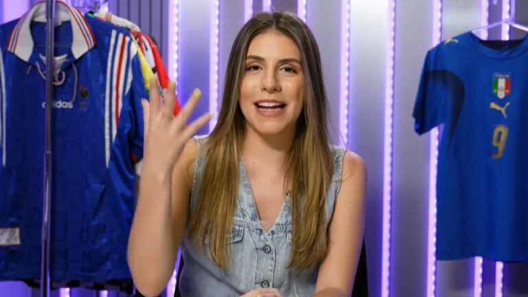 Apresentadora gesticula em estúdio esportivo com camisas das seleções da Itália e França penduradas ao fundo