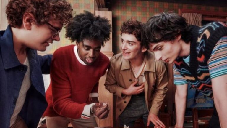 Quatro jovens estão reunidos em uma sala com decoração retrô, observando algo com atenção sobre uma mesa. Um deles segura um dado, sugerindo que estão jogando um jogo de tabuleiro. O ambiente tem papel de parede xadrez e iluminação quente, transmitindo uma atmosfera nostálgica e divertida.