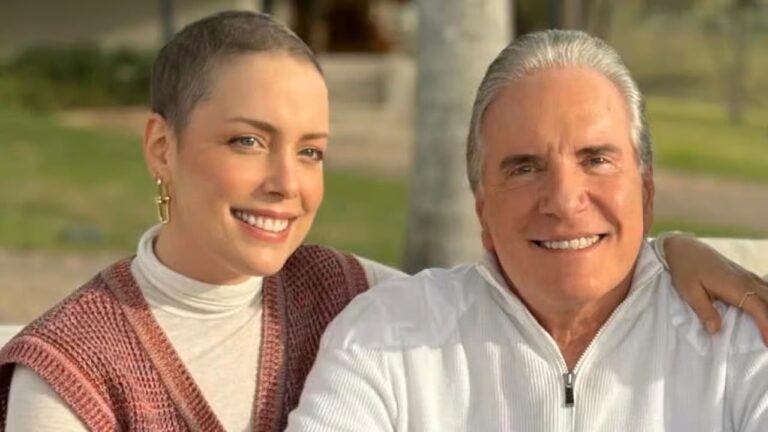 Mulher de cabelo curto e homem de cabelos grisalhos sorriem abraçados em ambiente externo iluminado pelo sol