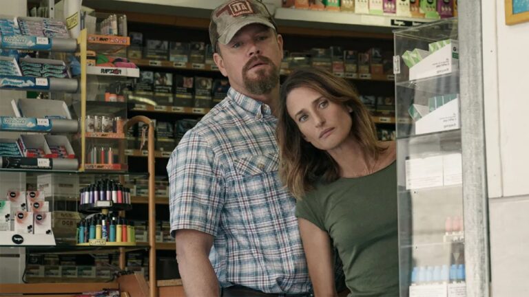 Homem de boné e mulher de camiseta verde observam atentos em cena de filme ambientada em loja