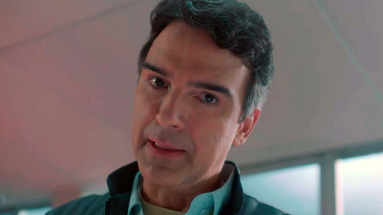 Tadeu Schmidt com expressão séria e olhar fixo durante chamada do BBB 26 ambientada em um laboratório com luzes em tons de azul