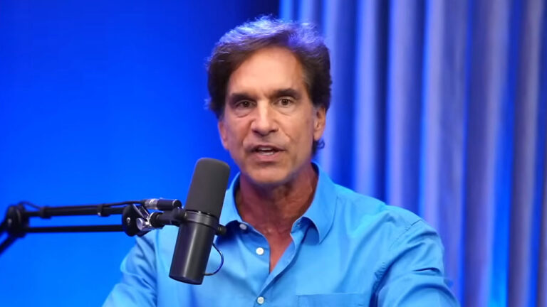 Victor Fasano fala ao microfone em estúdio de podcast com camisa azul e iluminação azul ao fundo