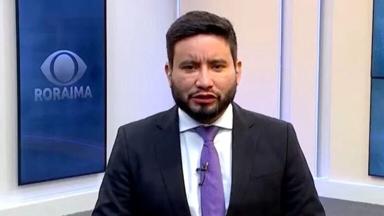 Apresentador da Band Roraima fala ao vivo no estúdio com logotipo da emissora exibido ao fundo