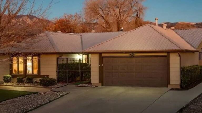 Casa térrea com telhado metálico e garagem dupla iluminada ao entardecer em bairro residencial