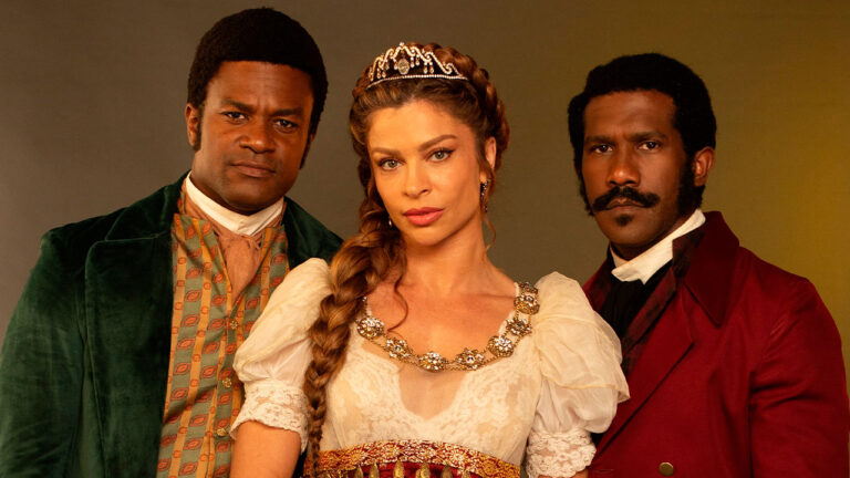 Grazi Massafera como Dona Beja ao centro com vestido de época e tiara entre Antônio Sampaio (David Junior) e João Carneiro (André Luiz Miranda) em foto de divulgação da novela Dona Beja