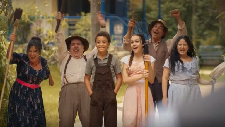 Elenco da novela Êta Mundo Melhor! comemora com ferramentas nas mãos em cena ambientada no interior durante sequência de união da comunidade