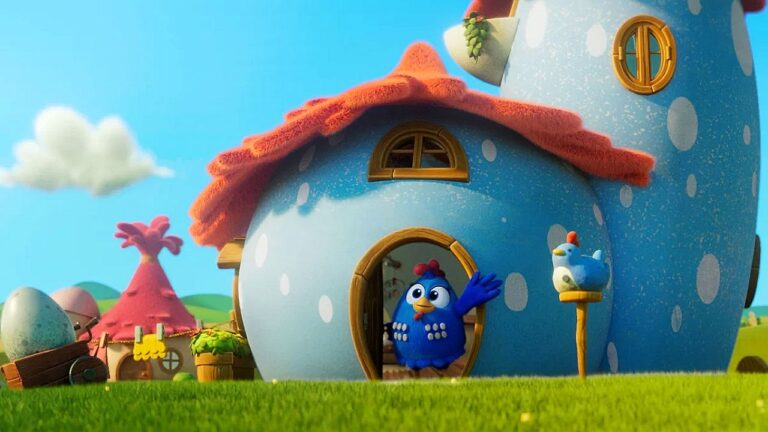 Cena de animação mostra galinha azul acenando na porta de uma casa redonda azul com bolinhas brancas e telhado vermelho. O cenário é colorido e infantil, com gramado verde, céu azul, nuvens e outras casinhas ao fundo, sugerindo ambiente lúdico de desenho animado.