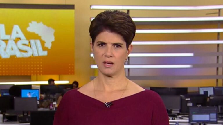 Mariana Godoy apresenta o Fala Brasil, veste blusa bordô em cenário de redação com monitores ao fundo e telão amarelo com o mapa do país à esquerda
