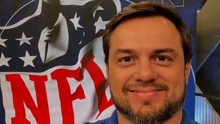 Apresentador posa diante de painel com logotipo da NFL durante cobertura esportiva em estúdio de TV