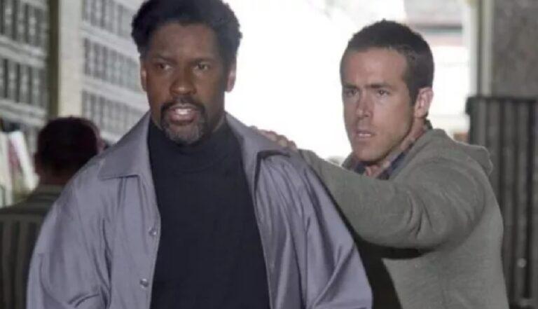 Dois homens caminham lado a lado em ambiente urbano fechado, com expressão tensa; um deles apoia a mão no ombro do outro, sugerindo situação de urgência ou confronto.