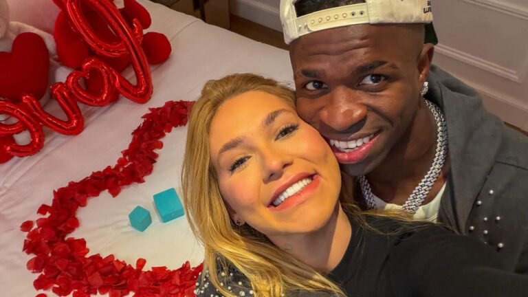 Virginia Fonseca e Vini Jr sorriem em selfie com rostos colados em quarto decorado com pétalas de rosas vermelhas em formato de coração sobre a cama