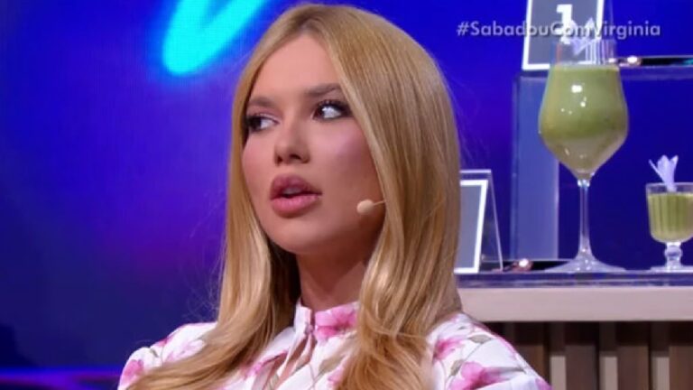 Apresentadora de cabelo loiro e roupa florida fala com microfone de lapela durante programa Sabadou com Virgínia