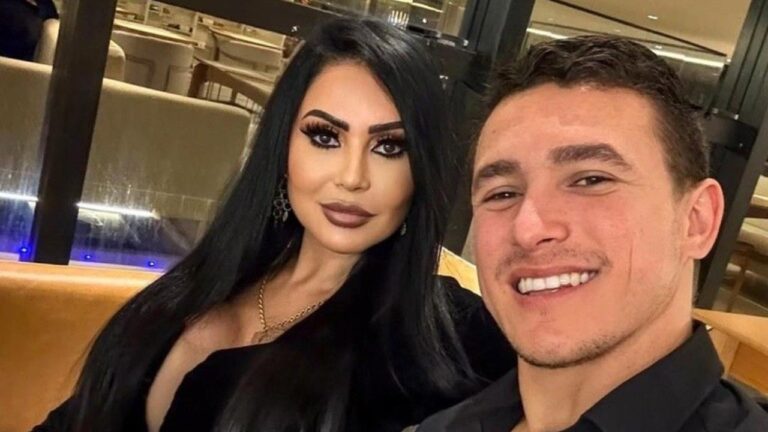 Ana Paula Oliveira e Luan Salgado posam juntos em selfie em restaurante com roupas escuras e iluminação ambiente ao fundo